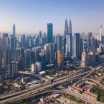 Aerial view of Kuala Lumpur Downtown, Malaysia and highways road. Financial district and business centers in smart urban city in Asia. Skyscraper and high-rise buildings at noon with blue sky.