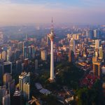 Menara Kuala Lumpur Tower with sunset sky. Aerial view of Kuala Lumpur Downtown, Malaysia. Financial district and business centers in urban city in Asia. Skyscraper and high-rise buildings at noon.